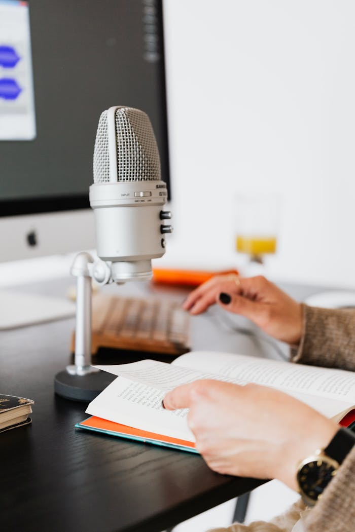 Hands holding a book near a microphone, perfect for recording or podcast scenes.